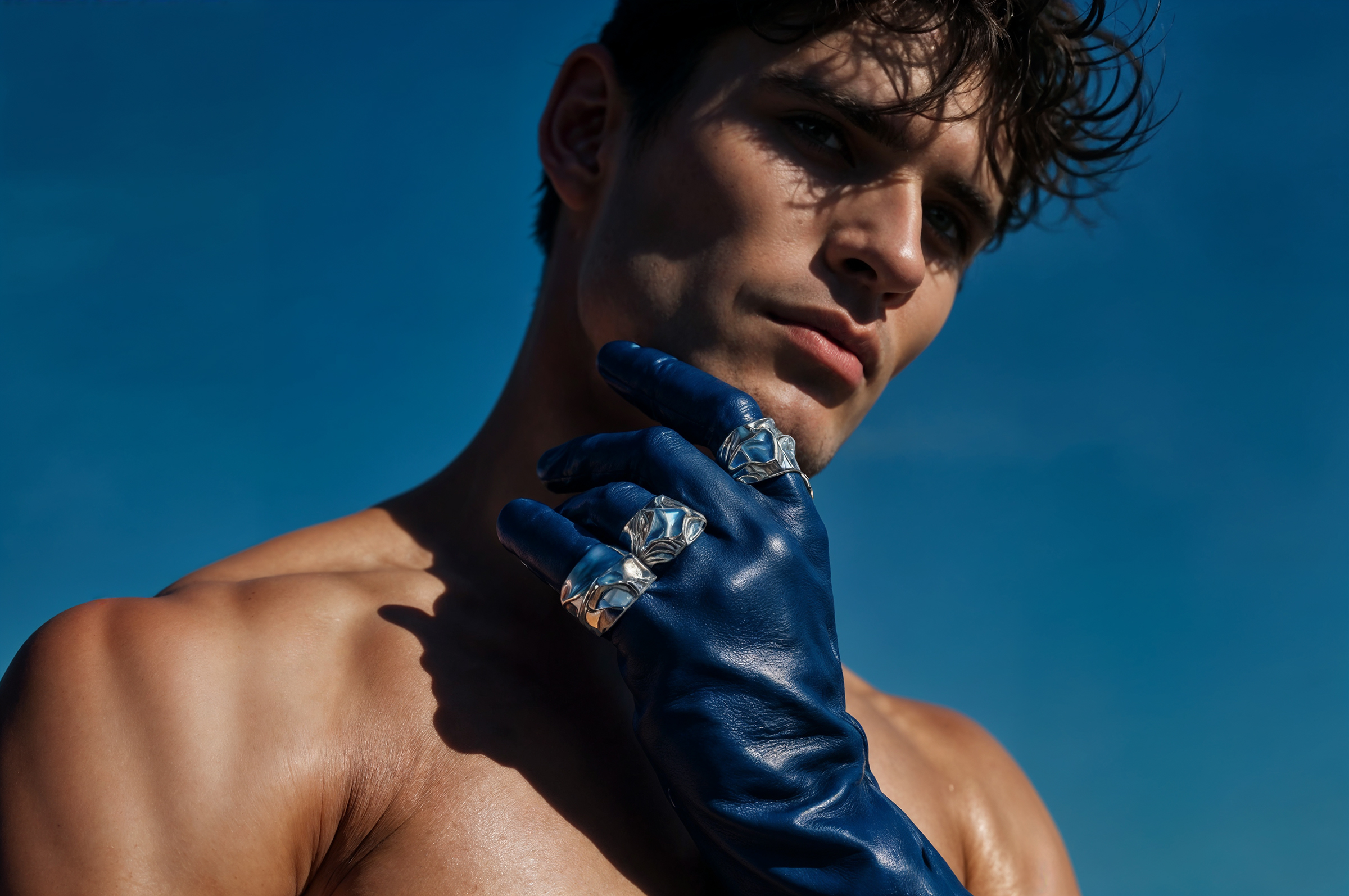 Un uomo a torso nudo che indossa guanti di pelle blu.